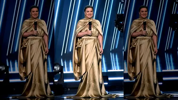 Kelly Clarkson on stage in a draped gold gown