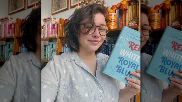 Casey McQuiston holding their book