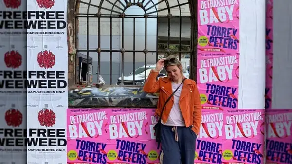 Torrey Peters posing with their book posters