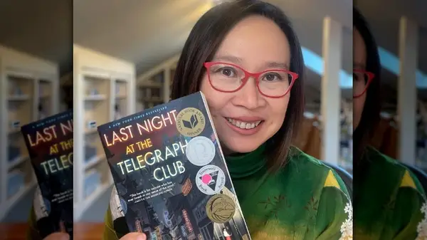 Malinda Lo holding her book