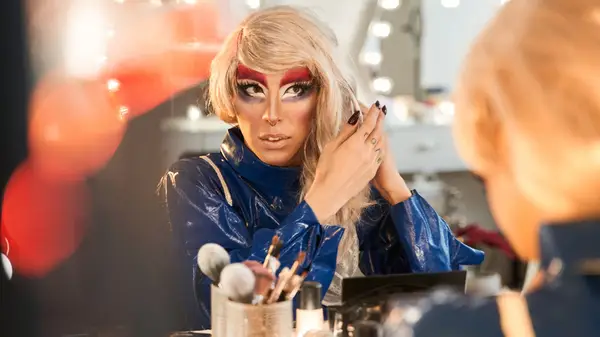 Drag queen applying makeup in mirror