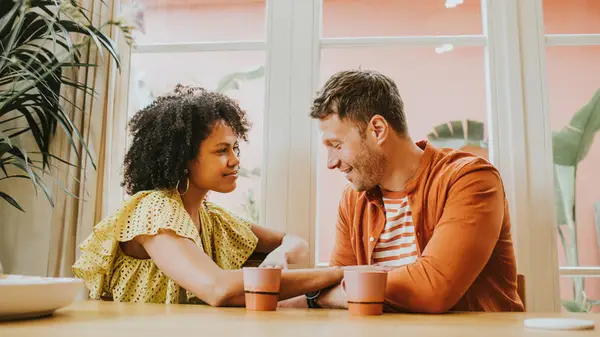 A couple sitting and holding hands at a table with coffee