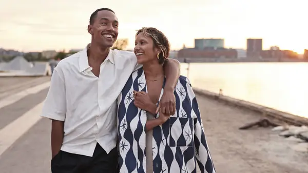 A couple walking and the man has his arm over his partner