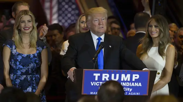 Melania Trump and Ivanka Trump stand flanking Donald Trump as he speaks at a podium