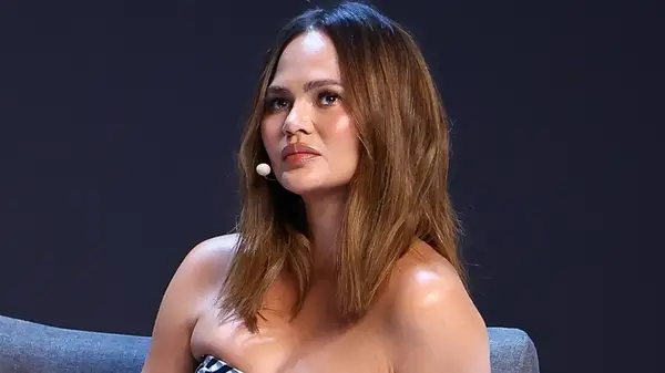 Chrissy Teigen wearing head microphone looking neutral