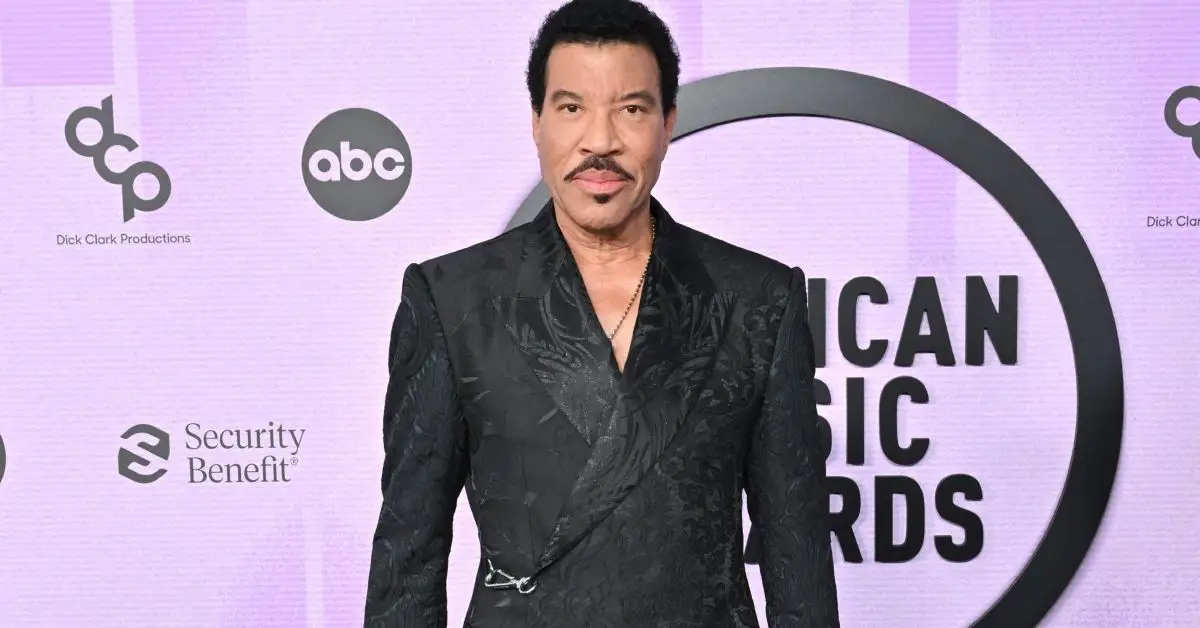 Lionel Richie debout sur le tapis rouge sur fond violet