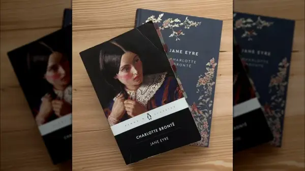 Two different editions of the book Jane Eyre on a wooden table