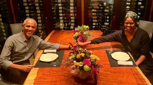 Barack Obama and Michelle Obama holding hands over a table