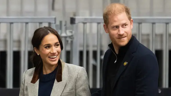 Prince Harry and Meghan Markle walking past metal barriers