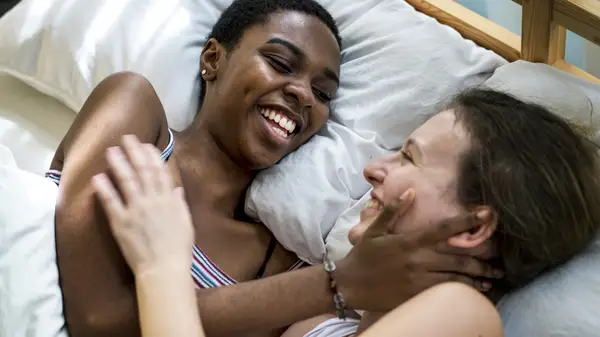 two women embracing in bed