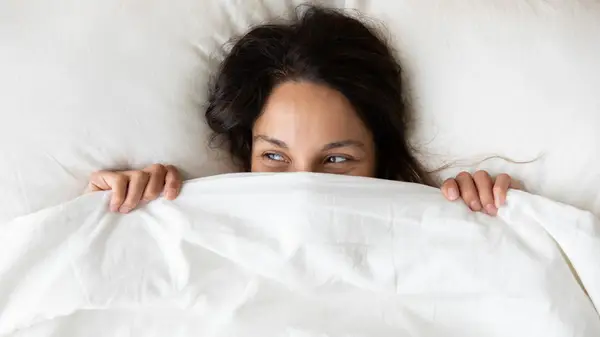 woman hiding under covers