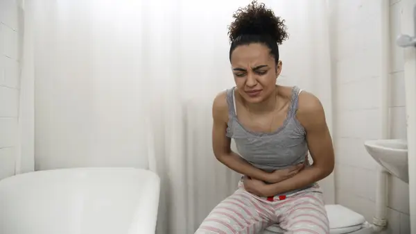 Holding stomach on toilet