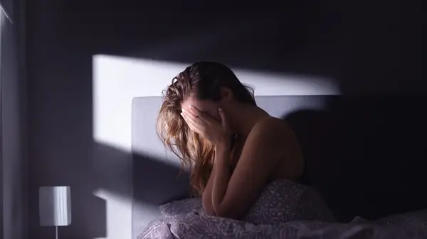 A woman crying into her hands in the dark