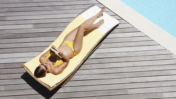 Woman reading book by pool