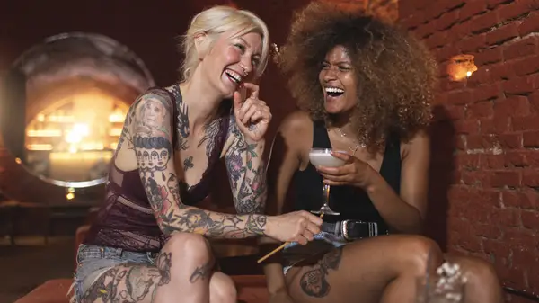 two women in a bar laughing together