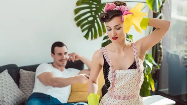 Woman cleaning and man watching TV