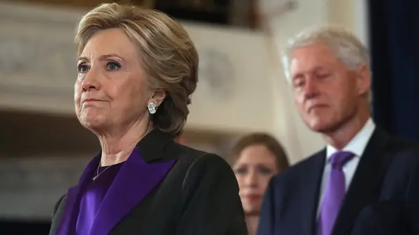 Hillary Clinton standing in front of Bill Clinton