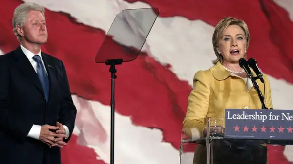 Bill Clinton standing behind Hillary Clinton