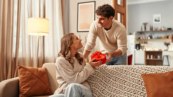 Flat lay shot of hands holding a package with heart wrapping paper and red ribbon