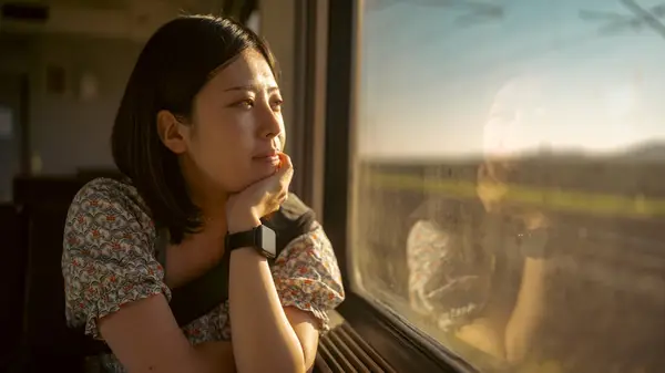 Woman stares wistfully out window 