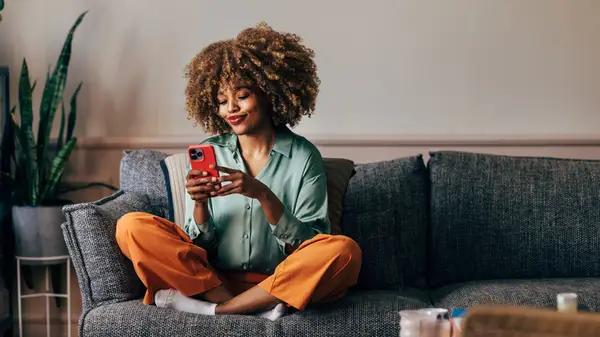 Woman sitting on couch holding phone