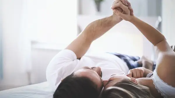 Couple holding hands in bed