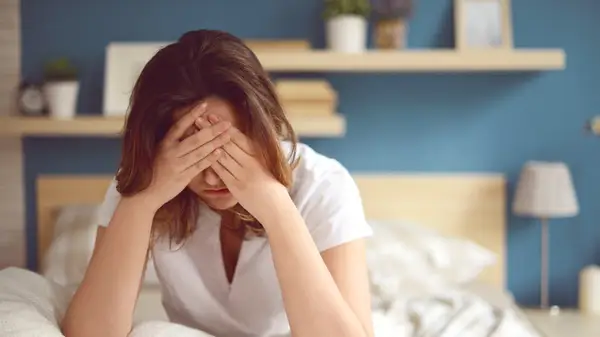 woman holds head in hands