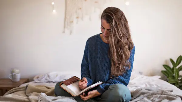 Woman writing in a journal in bed