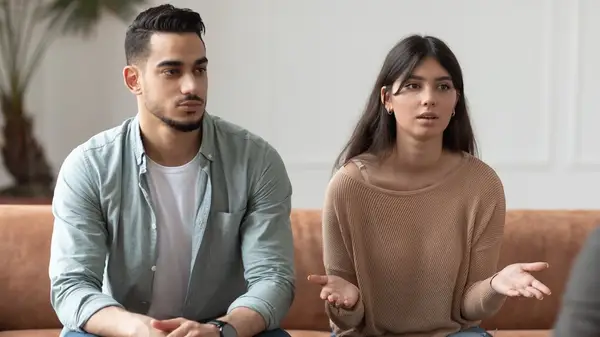 Couple talking, seated on sofa