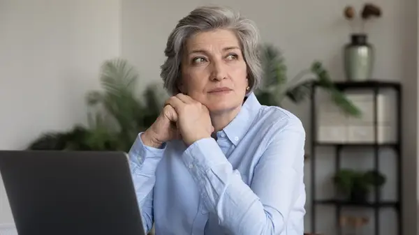 Woman thinking, looking away, hands resting on chin