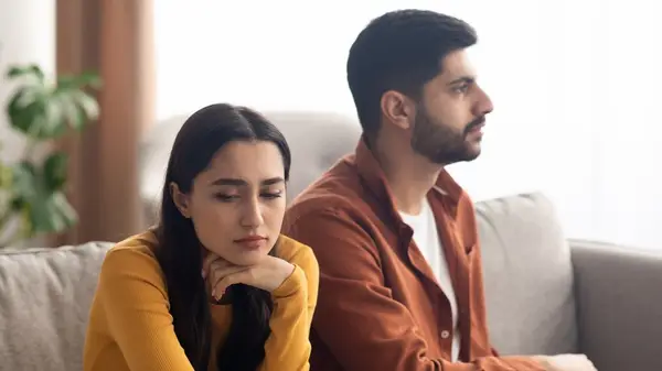 An unhappy couple seated on sofa