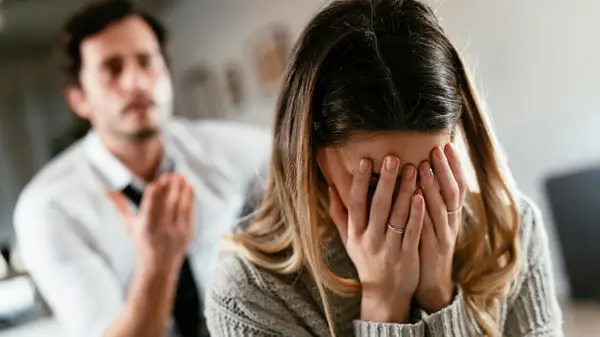 Woman covering her face as a man talks