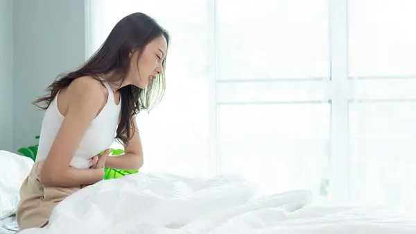 Woman in bed looking uncomfortable