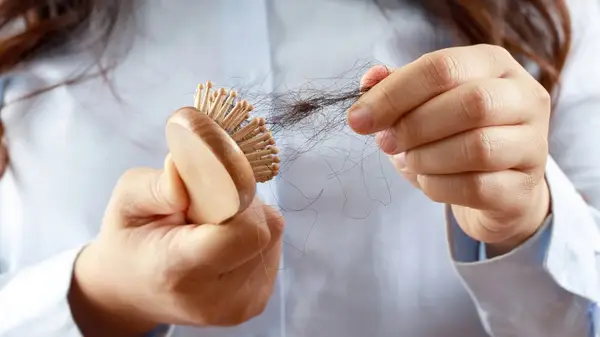 woman pulling hair from hairbrush