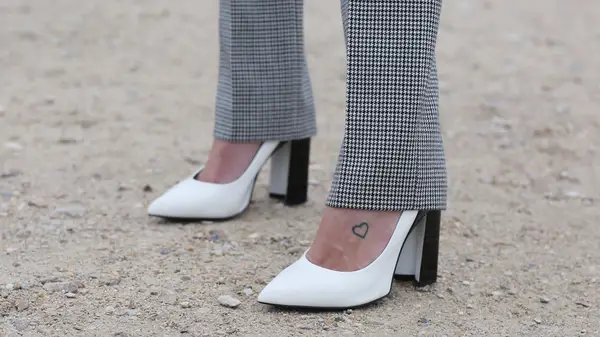 tattoo of a heart on a foot wearing white high heels