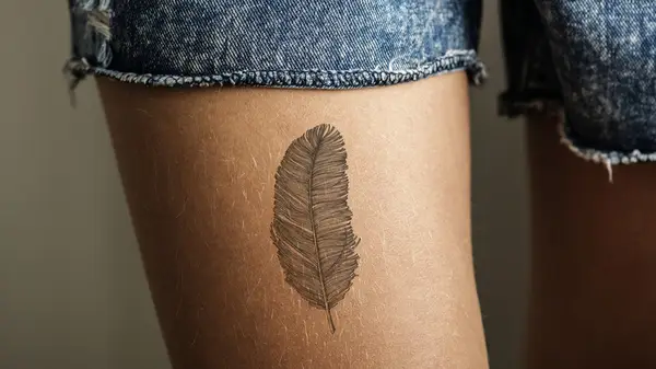 tattoo of feather on a woman