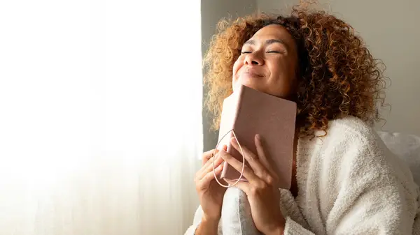 Woman smiling and holding her journal to her chin
