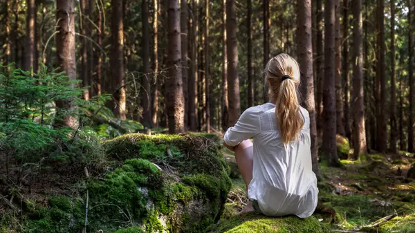 Woman sitting barefoot in forest