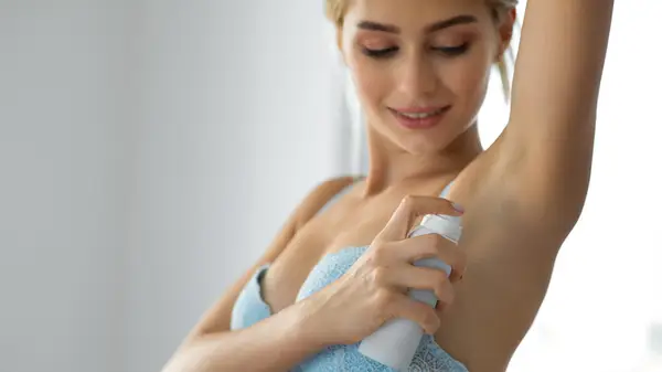A woman putting on deodorant