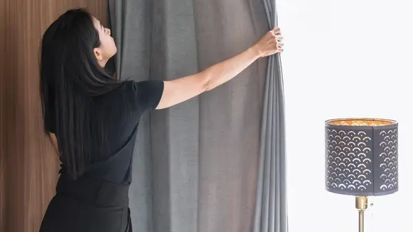 Woman closing curtains