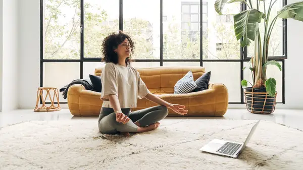 Woman meditating in front of laptop