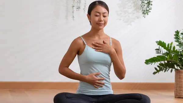 Woman on mat hands on heart and belly
