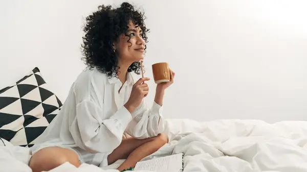Woman journaling in bed with coffee