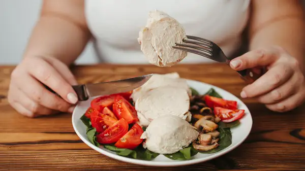 Person eating chicken and veggies
