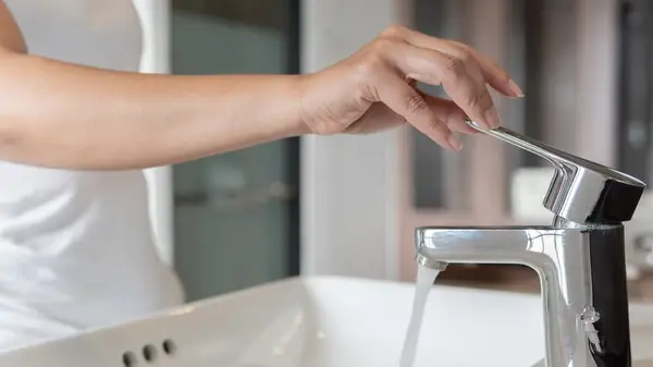 Woman turning off faucet