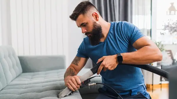 Man vacuuming couch